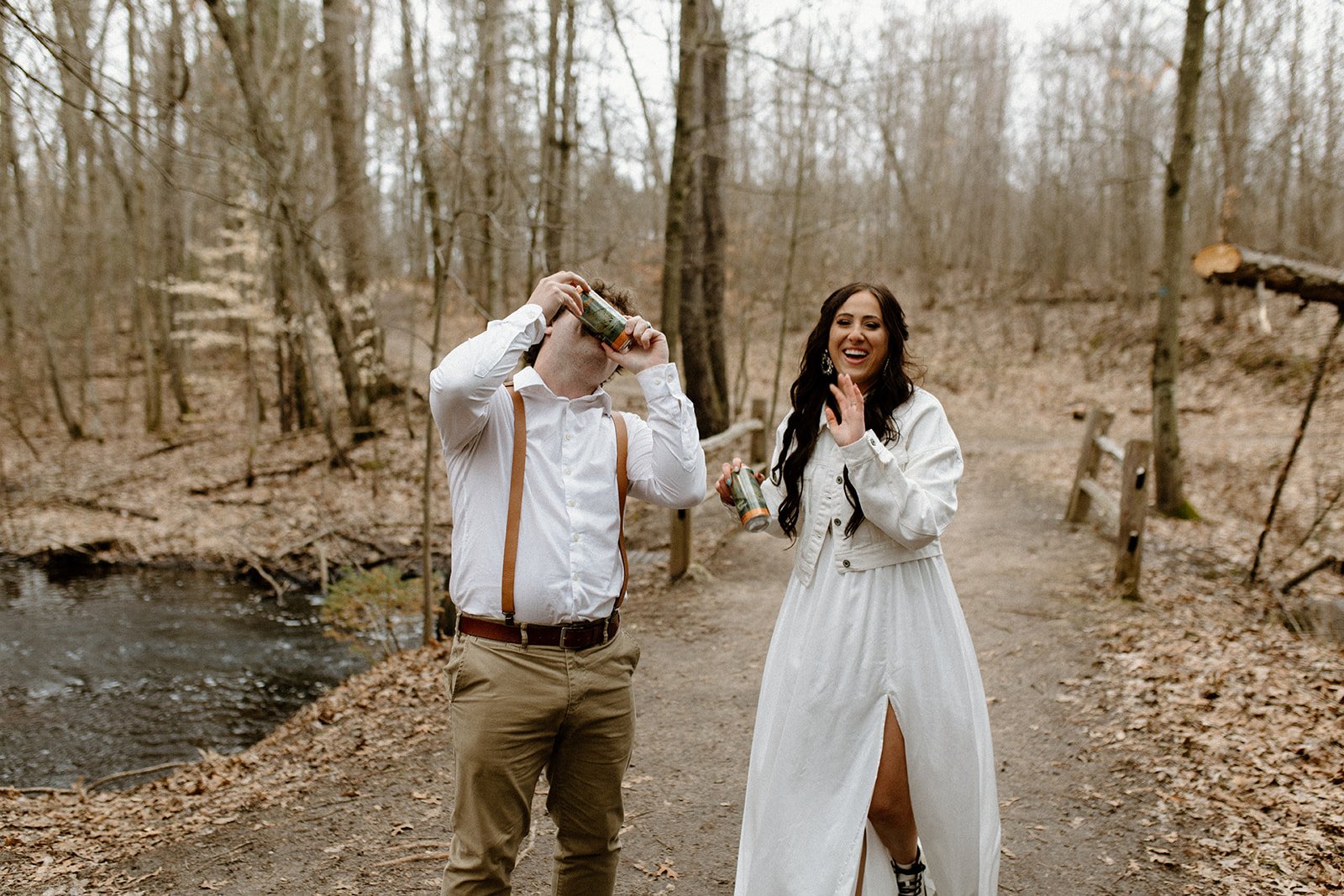kennedy and joey shotgunning beers to celebrate their adventure elopement at north country trail