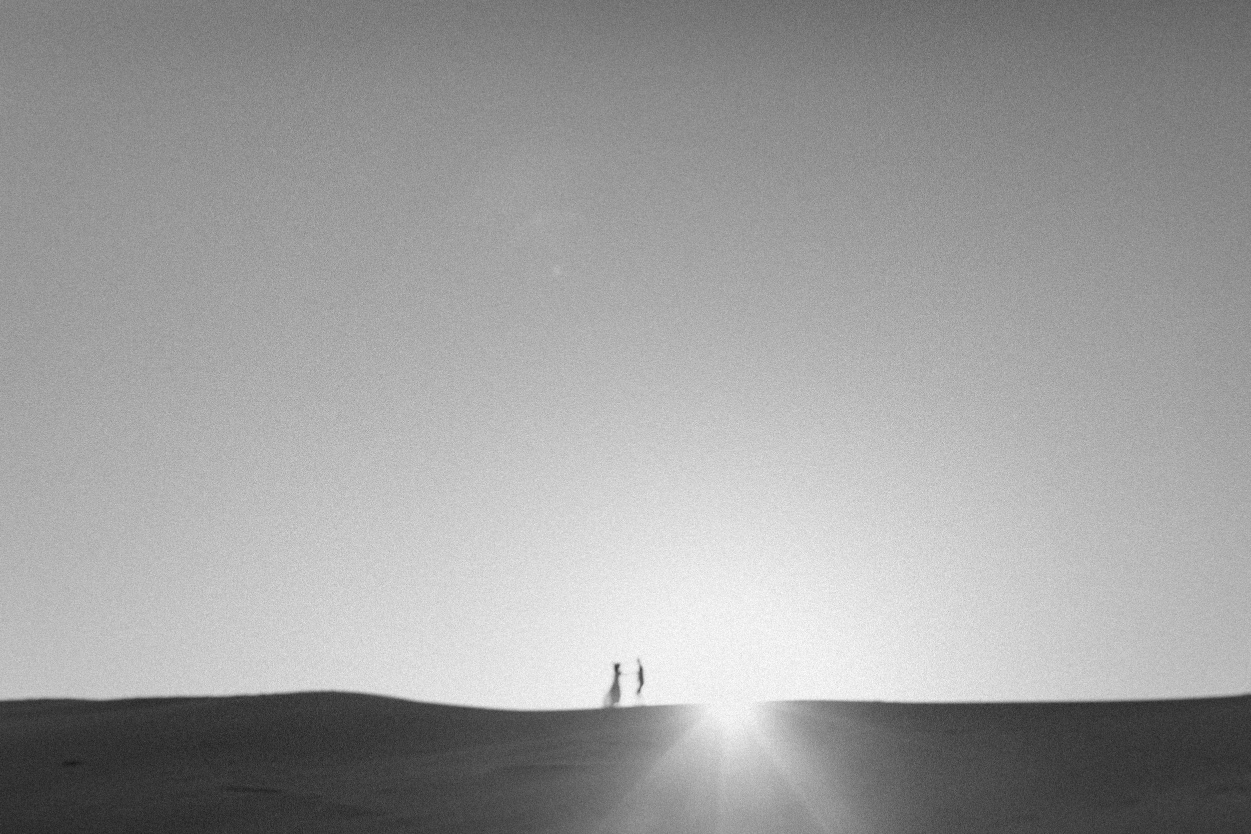 Dancing in front of the sunset on the dunes in black and white